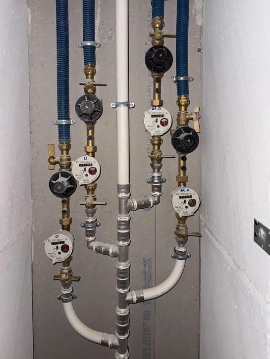 Technicien en salopette bleue effectuant la maintenance d'un radiateur à ailettes dans un intérieur résidentiel moderne